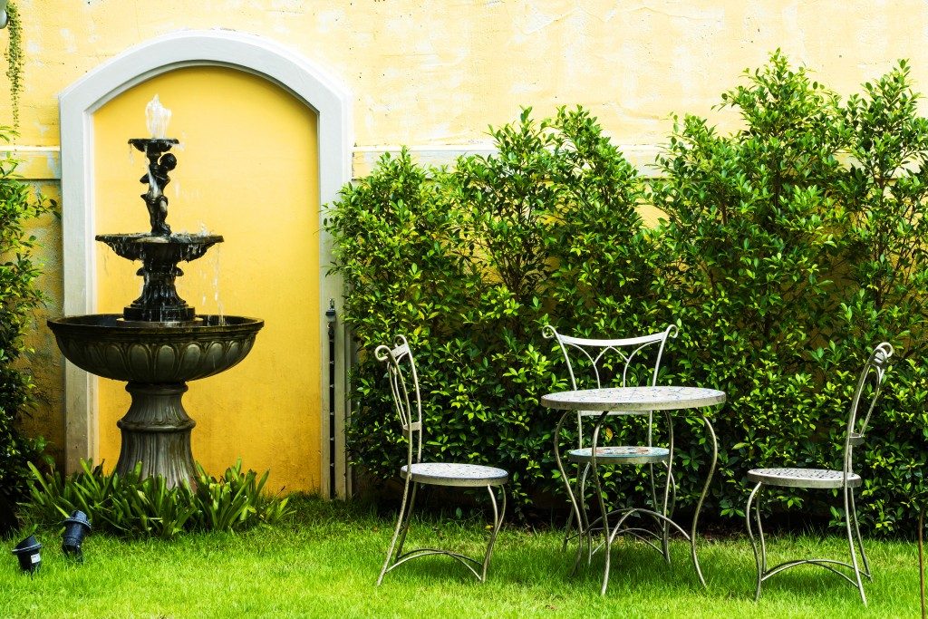 A simple garden with a fountain, a table and a chairs