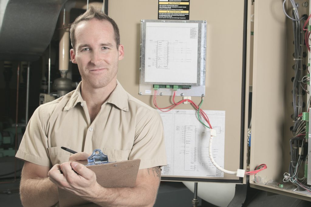 an HVAC tehnician smiling after a routine check