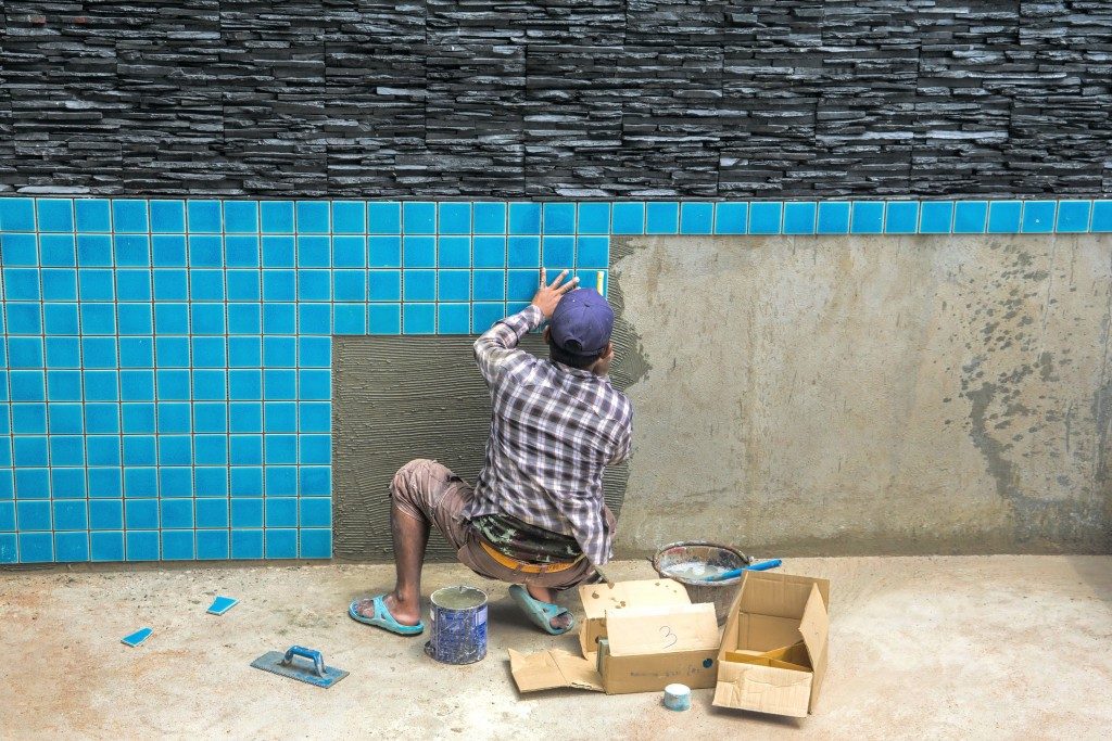 man installing tiles to new pool