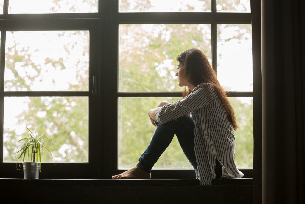 gloomy girl sitting near the window